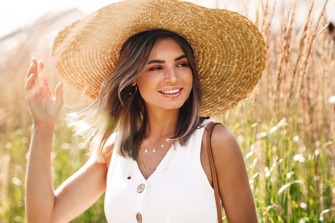 Happy woman in sunhat enjoying a sunny day in the field
