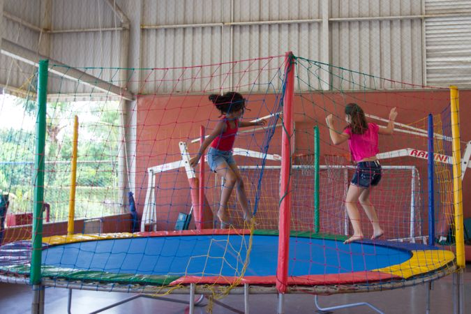 Two young girls jumping on trampoline