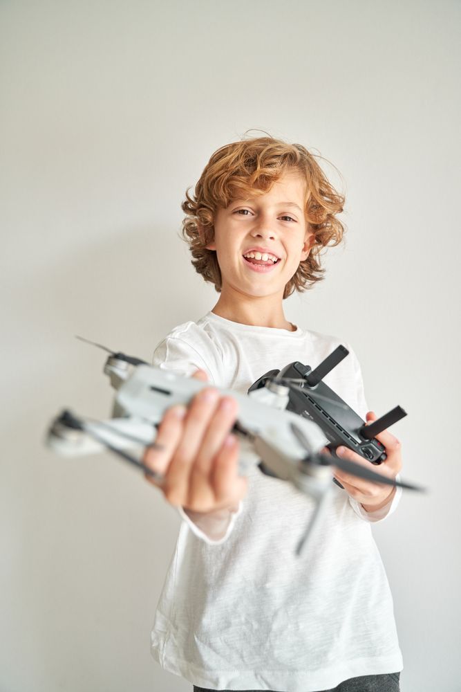 Cheerful preteen boy showing drone copter with remote control