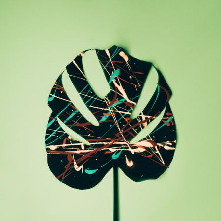 Monstera leaf painted in neon colors on pastel green background
