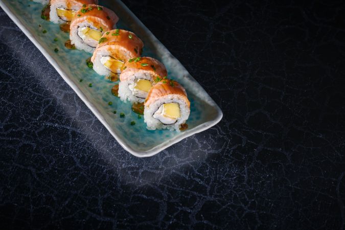 Delicious sushi rolls on marble plate in dark studio
