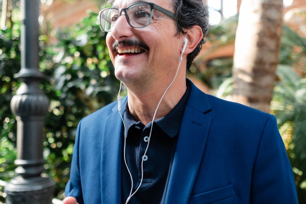 Mature businessman using smartphone with headphones and smiling