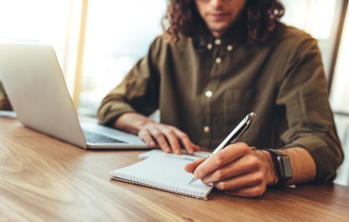 Entrepreneur making notes sitting at his work desk in office