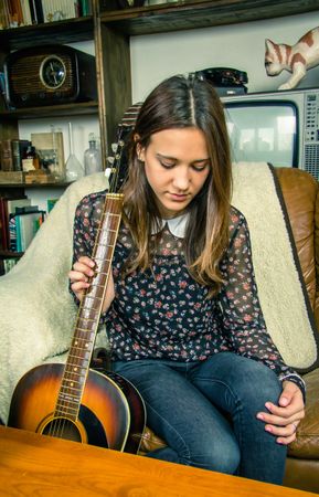 Young hipster woman with acoustic guitar at home