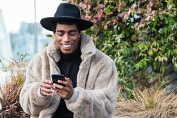 Stylish happy man with smartphone on street