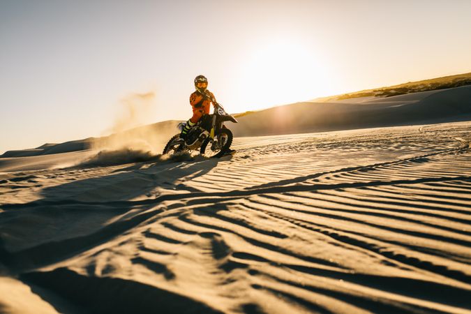 Man riding down hill in desert on bike and making a turn