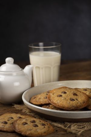 Delicious chocolate cookies with glass of milk on wooden table.