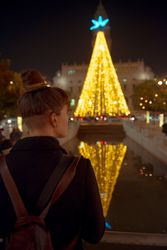 Anonymous woman looking at bright Christmas tree