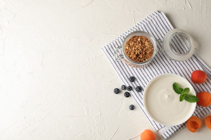 Composition with granola, yogurt and fresh fruits on cement background