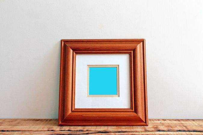Square wooden picture frame on desk mockup