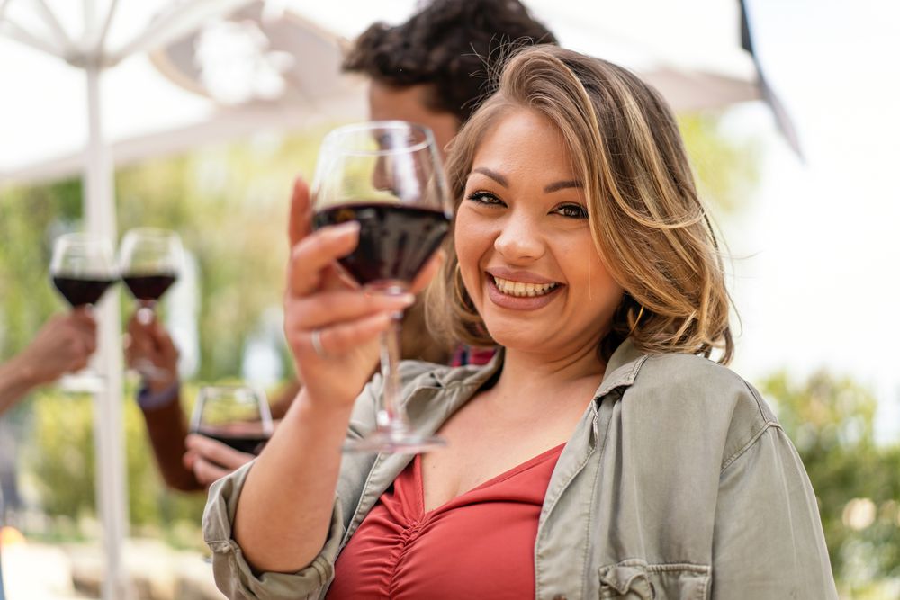 A radiant woman raises her glass for a toast, smiling