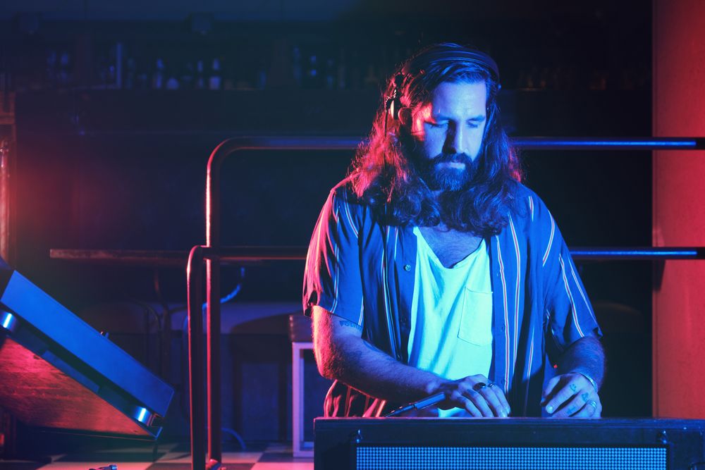 Bearded man playing on DJ mixer
