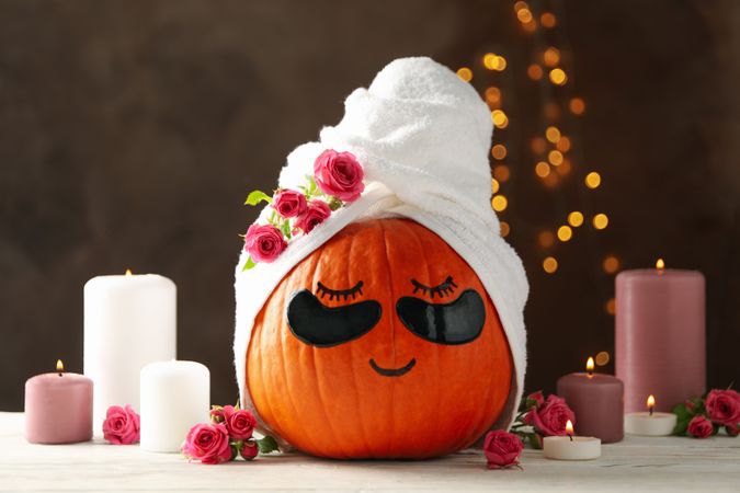 Candles and pumpkin with eye patches on brown background
