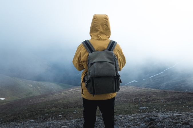 Anonymous traveler on hill on misty day