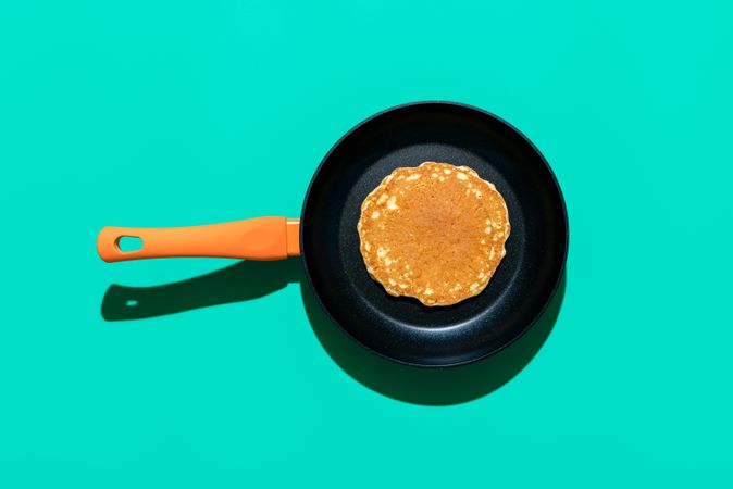 Pancake in a iron cast pan, top view on a green colored background