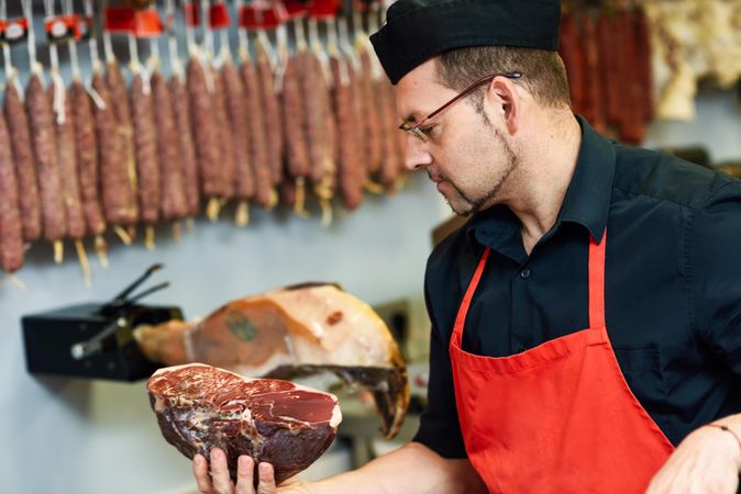 Man in butcher shop holding cut meat