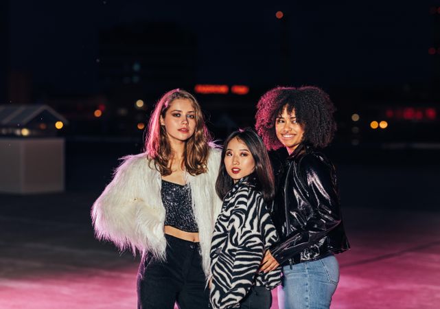 Multi-ethnic group of trendy women on roof top at night with pink light