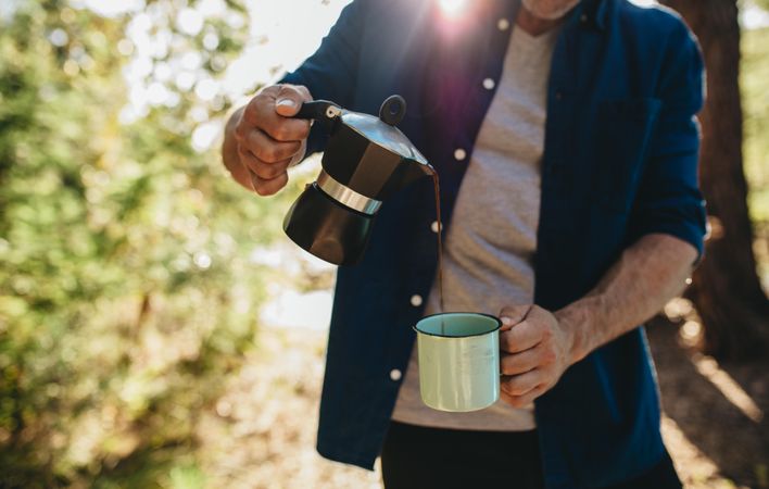 Man pouring fresh coffee while camping outdoors