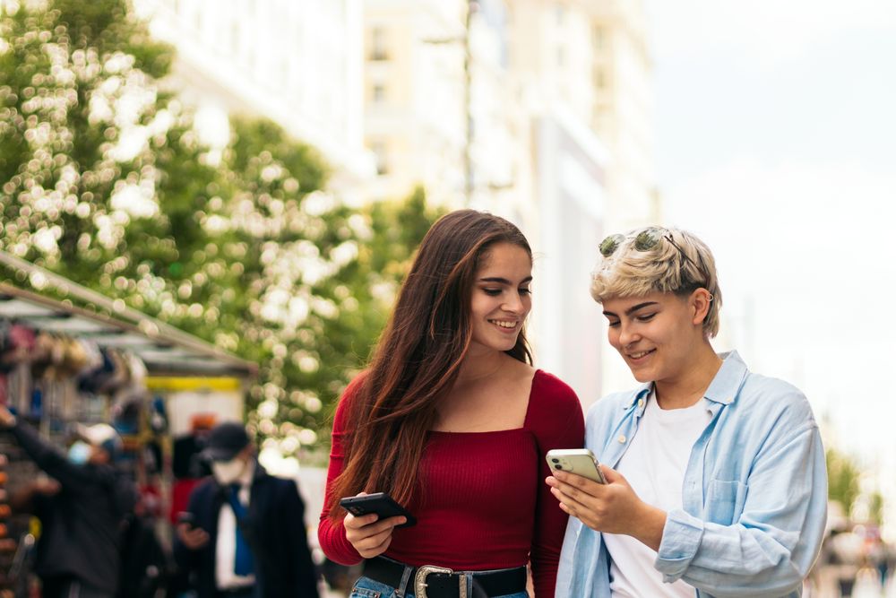 two women walking and watching mobile