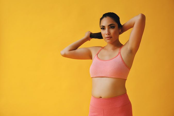Hispanic woman in yoga clothes looking in the distance putting her hair up, copy space