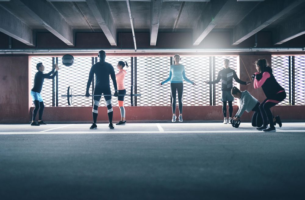 Multi ethnic group of people doing circuit training in a covered car park