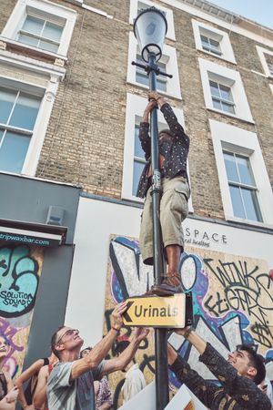 London, England, United Kingdom - August 25th, 2019: Man standing on streetlight in London