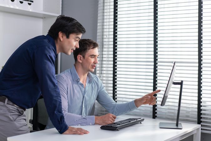 Two corporate colleagues talking together over screen in the workplace