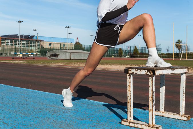 Female athlete stretching on stool on stadium