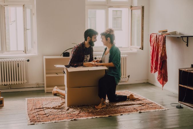 Couple having fun while unpacking boxes at home