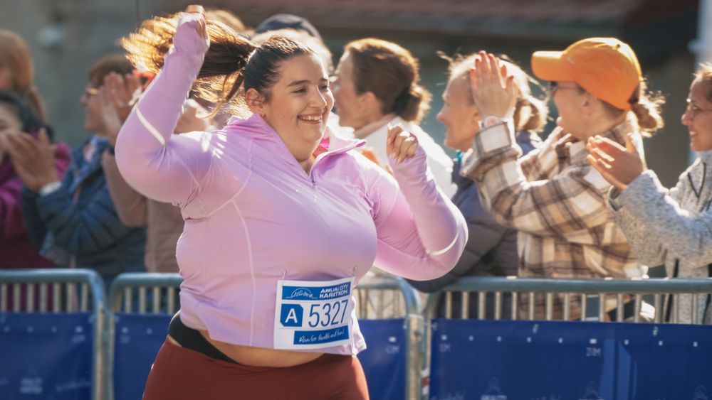 Portrait of a Smiling Female Runner Crossing the Finish Line and Demonstrating her Willpower.