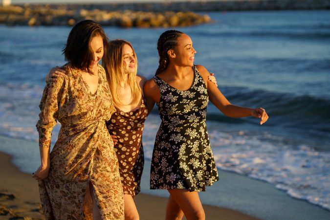 Women friends walking along the shore at magic hour