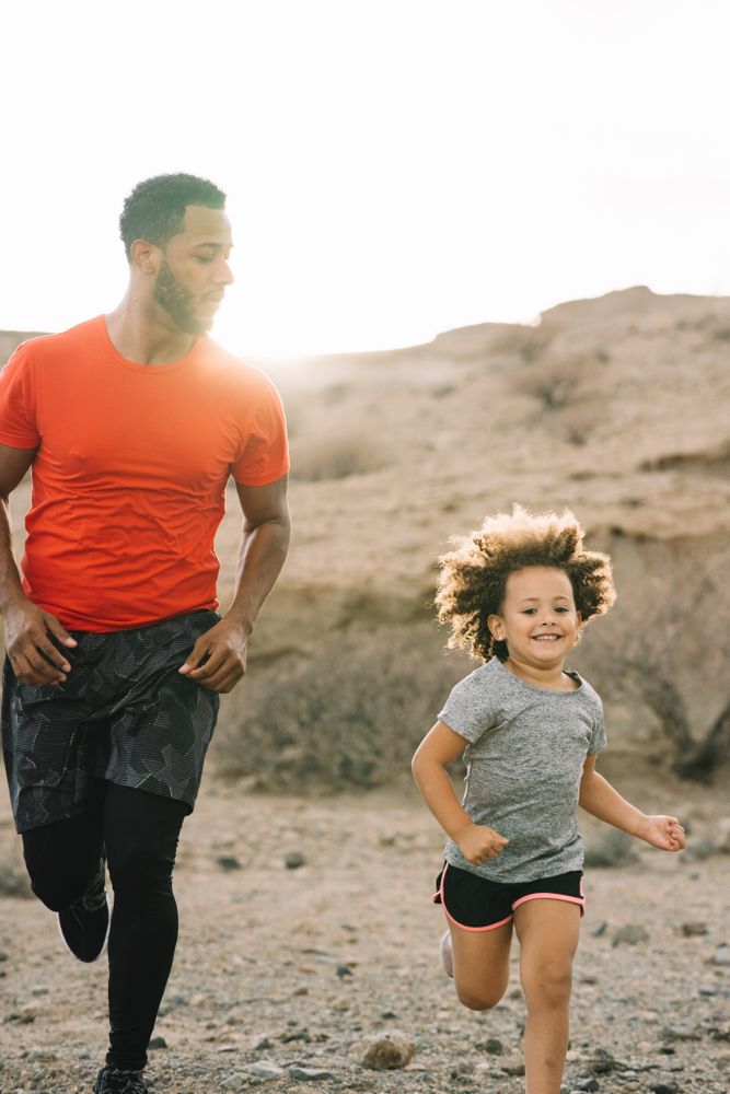 Black man jogging with toddler on nature