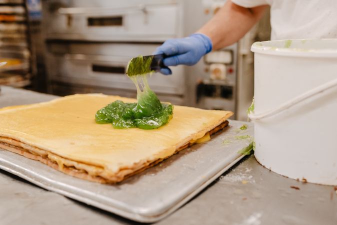 Crop baker putting jelly on cake