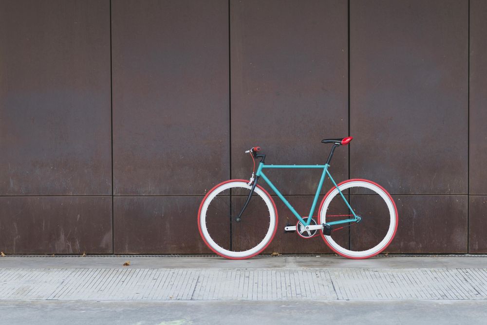 Red and green bicycle parked against a brown wall, copy space
