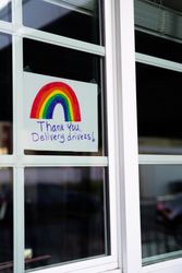 Handwritten sign taped to home window with panes thanking delivery drivers during lockdown