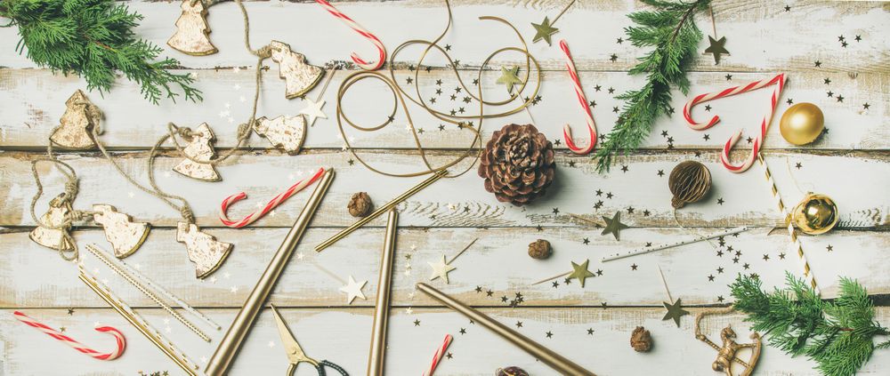 Decorations of stars, candy canes, scissors, candles on light background, wide composition