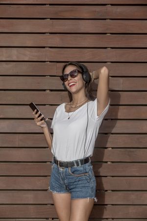 Woman wearing sunglasses and listening to music on headphones