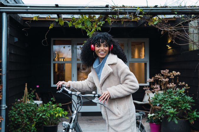 Cheerful Black woman in headphones with bicycle