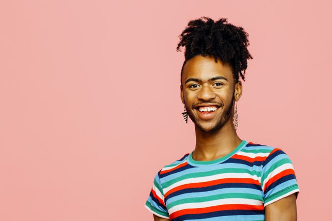 Portrait of a young Black man with a big smile, looking at camera, isolated on pink background