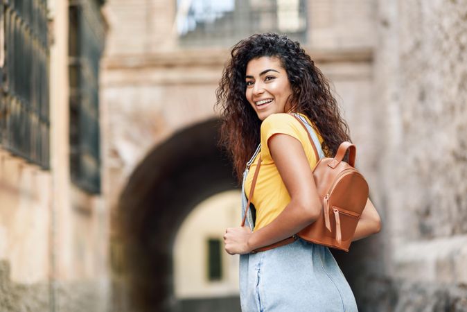 Happy Arab woman walking outside towards arch