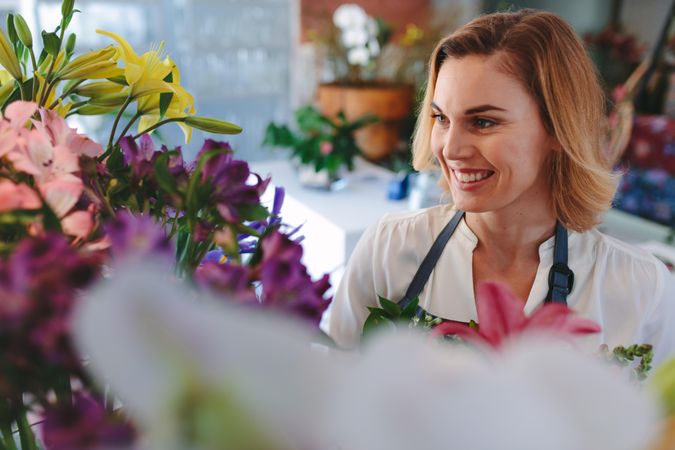 Smiling florist looking at flowers in her shop