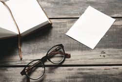 Notebook, paper and glasses on wooden table