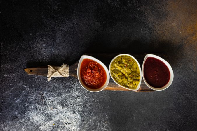 Top view of three flavorful spicy traditional Georgian sauces on dark counter with copy space