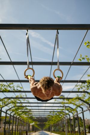 Strong young sportsman exercising with rings