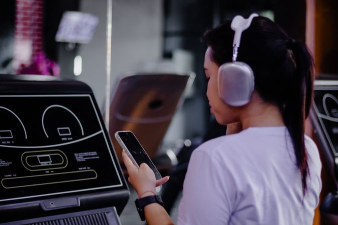 Woman Enhancing Gym Routine with Smartphone and Wireless Headphones