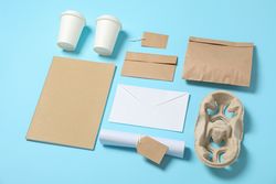 Composition with paper cups and office supplies on blue background, copy space
