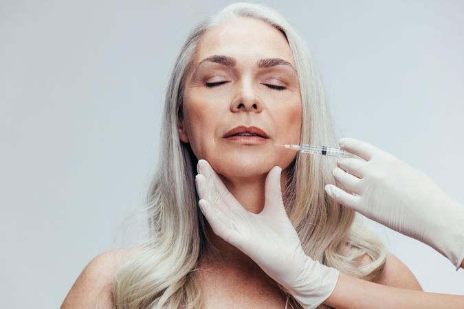 Woman getting injections against grey background