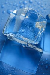 Close up shot looking down at melting ice cubed on blue table