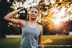 Portrait of fit young woman with kettlebell weights in the park bYO265