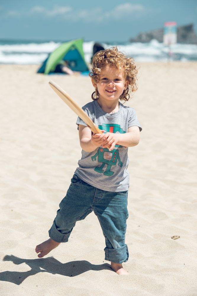 Delighted boy with racket on seashore